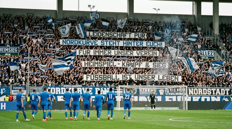 Gefüllte Heimtribüne hinter dem Tor und Spieler auf dem grünen Rasen eines deutschen Fußballstadions während eines Bundesliga-Heimspiels