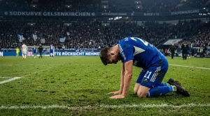 Bundesliga-Spieler kniet nach dem Abpfiff niedergeschlagen auf dem Rasen